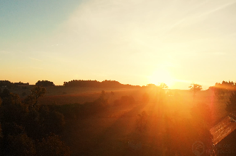 Aerial view of the French countryside at sunrise, with golden sunlight illuminating the landscape